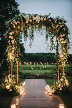 an outdoor wedding ceremony with candles and flowers on the aisle, surrounded by greenery