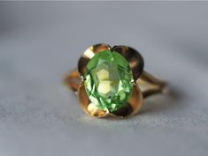 This arresting vintage ring is crafted with a body of solid 18kt gold, warm and lovely, with an open, dramatic scalloped setting and grooved band. In the centre, a radiant seafoam-green Synthetic Spinel that seemingly glows with its own inner light. The colour of the spinel is truly ethereal and otherworldly, so dreamy and spring-like when the sun hits it just so.  The stone itself measures approx. 9.5 x 8 x 4 MM in dimension, while the setting measures approx. 12.5 MM north to south along the f Elegant Concave Gemstone Rings, Elegant Wedding Watch With Fluted Bezel, Elegant Wedding Jewelry With Fluted Bezel, Formal Oval Jewelry With Fluted Bezel, Elegant Gold Rings With Fluted Bezel, Vintage Yellow Gold Ring For May Birthstone, Vintage Yellow Gold Rings With May Birthstone, Gold Oval Ring With Fluted Bezel, Vintage Yellow Gold Rings For May Birthstone