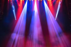 several spotlights are shining brightly on a stage with red, white and blue lights