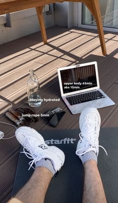 a person sitting on a yoga mat with their feet propped up in front of a laptop