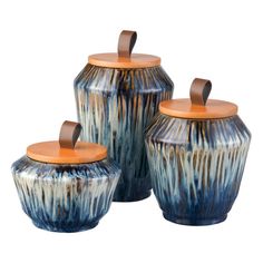 three ceramic jars with wooden lids are shown in blue and brown colors, one has an orange lid