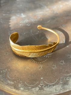 21 ct gold plated brass. Feather design bangle cuff                            Designed by our Turkish designer. Handcrafted with great care. Gold-tone Brass Bangle, Gold-tone Brass Bangle As Gift, Bohemian Gold Bangle For Gift, Gold Brass Bangle As Gift, Bohemian Gold Bangle As Gift, Handmade Gold Plated Bangle Cuff Bracelet, Bohemian Yellow Gold Bangle For Gift, Bohemian Yellow Gold Bangle As Gift, Gold Bohemian Bangle Cuff Bracelet