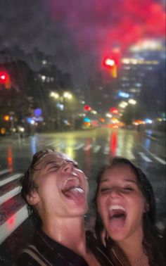 two people are laughing while standing in the rain