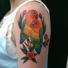 two birds sitting on top of each other on a tree branch with leaves and flowers