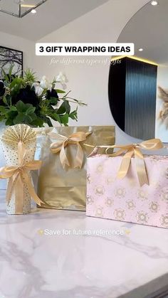 three wrapped gift bags sitting on top of a counter next to a vase filled with flowers