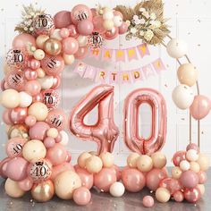 a pink and white balloon arch with the number forty on it, surrounded by balloons