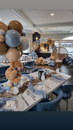 a teddy bear sitting on top of a table in a room filled with blue chairs