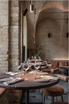 an empty restaurant with wooden tables and brown leather chairs, brick walls and exposed ceilings