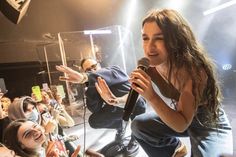 a girl singing into a microphone in front of a crowd