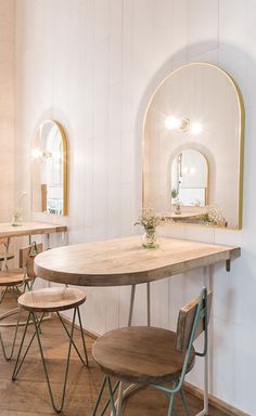 a dining room table with four chairs around it and a mirror on the wall behind it