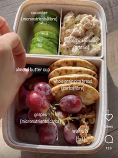 a lunch box with grapes, cucumber, chicken salad and crackers in it