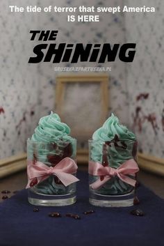 two cupcakes with green frosting and pink bows are on display in front of a mirror