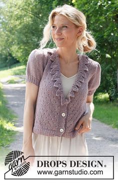 a woman standing on a dirt road wearing a cardigan