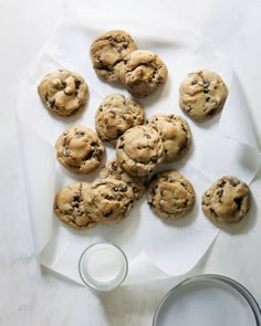 chocolate chip cookies and a glass of milk on a white tablecloth with napkins