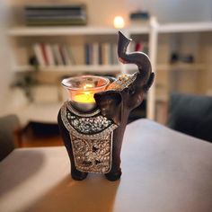 an elephant shaped candle holder sitting on top of a table next to a book shelf