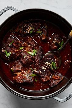 a pot filled with meat and sauce on top of a table