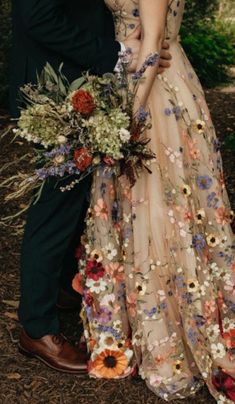 a man and woman standing next to each other in front of some trees with flowers on them