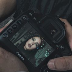 a person holding a camera with a woman's face on the screen in their hands