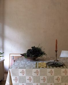 a dining room table with a potted plant in the center and candles on top