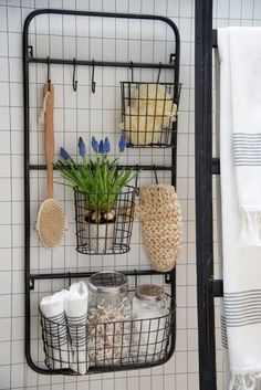 a black metal shelf with baskets and plants on it next to a white tiled wall