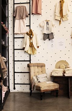 a room with clothes hanging on the wall, and a chair in front of it