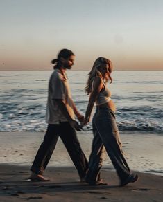 two people walking on the beach holding hands