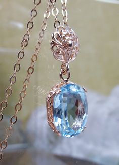 blue topaz pendant, with a natural blue topaz oval stone set in floral rose gold filigree, 4 prongs hold the gem in place Elegant Rose Gold Filigree Necklace, Rose Gold Sterling Silver Filigree Jewelry, Elegant Oval Pendant Jewelry With Blue Topaz, Elegant Oval Blue Topaz Pendant Jewelry, Elegant Blue Topaz Oval Pendant Jewelry, Exquisite Blue Topaz Necklace Gift, Exquisite Blue Topaz Necklace For Gift, Elegant Oval Pendant Topaz Jewelry, Elegant Oval Pendant Topaz Necklace