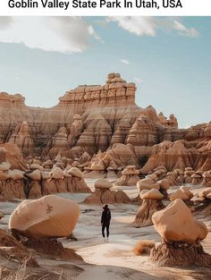 a person standing in the middle of a desert with large rocks and boulders behind them