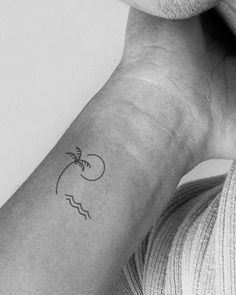 a black and white photo of a person's arm with a small tattoo on it