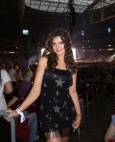 a woman in a black dress standing next to a metal pole at a sporting event