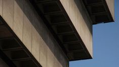 an airplane is flying in the air from underneath a bridge