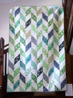 a green and white quilt hanging from a stair rail