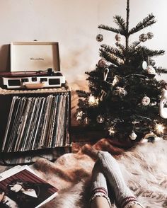 a woman's feet resting on the floor next to a christmas tree and record player