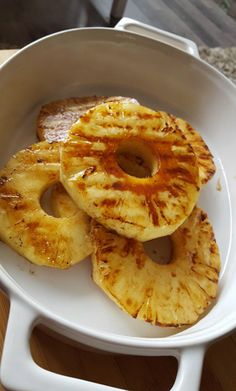 grilled pineapple slices in a white dish on a wooden table