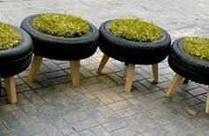 four black tires with grass growing in them