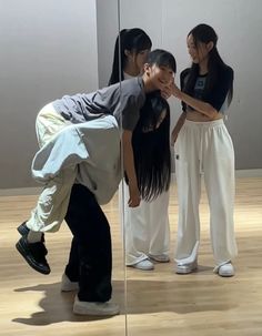 three people standing in front of a mirror with one person touching the other's face