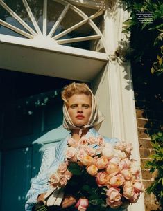 a woman holding a bouquet of flowers in front of a building with an arched doorway