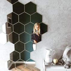 a woman is taking a selfie in the mirror next to a table and vase