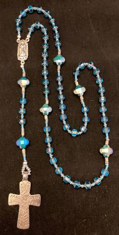 Hand made glass beaded in a teal/blue rosary with cross, center piece and small fabric pouch Blue Beaded Rosary As A Gift, Handmade Blue Rosary For Jewelry Making, Adjustable Blue Rosary With 8mm Beads, Blue Rosary With Round Beads For Healing, Blue Rosary With 8mm Beads For Healing, Handmade Blue Rosary With Cross Shape, Handmade Blue Rosary With Cross, Adjustable Blue Beaded Rosary, Blue 108 Beads Spiritual Rosary