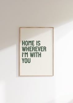 a white wall with a green print on it that says home is wherever i'm with you