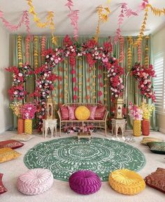 a living room decorated in pink, yellow and green with flowers on the wall behind it