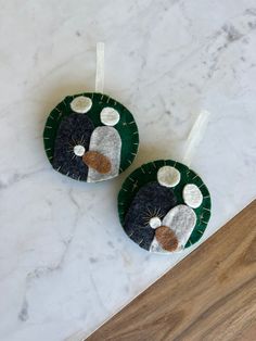 two ornaments made out of felt sitting on top of a marble counter next to each other