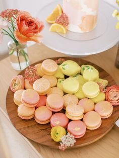 there is a plate full of colorful cookies on the table next to a vase with flowers