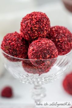 a glass bowl filled with raspberries on top of a table