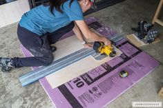 a woman is working on the floor with a drill