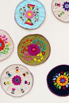 six embroidered plates are arranged on a white surface