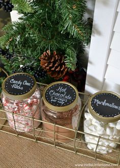 three jars filled with candy and marshmallows sitting on a shelf next to a christmas tree