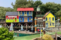 several colorful houses are on display in a park with water fountains and playgrounds for children to play