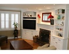 a living room with white furniture and a flat screen tv mounted on the wall above a fireplace