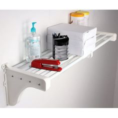 a white shelf with some items on it and a red object in the corner next to it